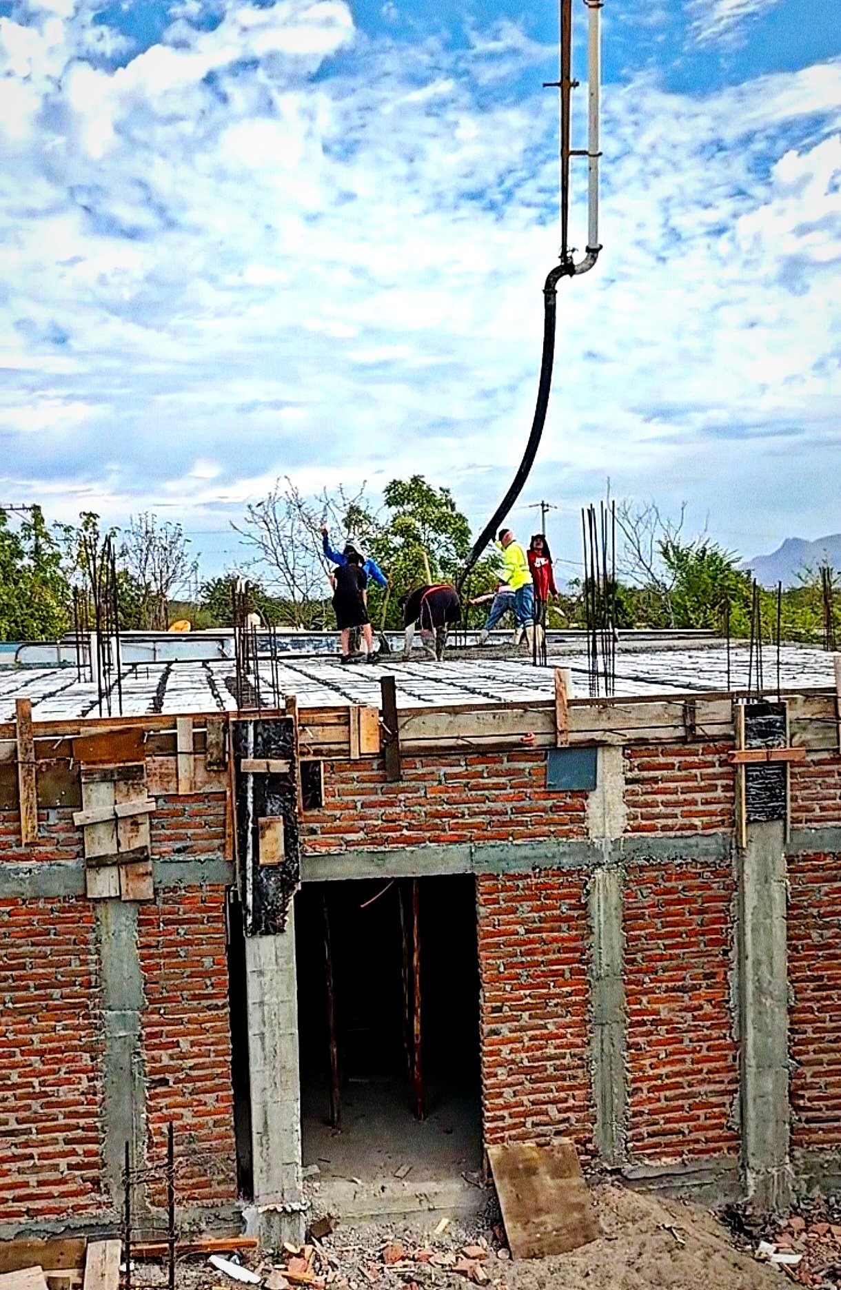 Colado con bomba pluma y su ayudante tirando concreto